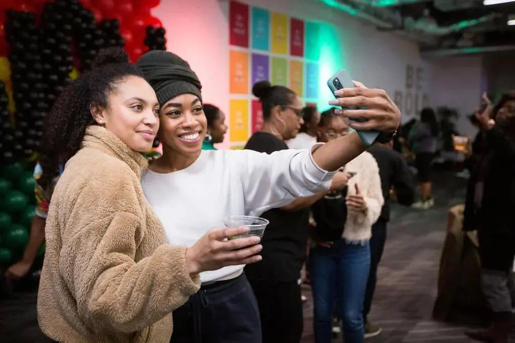 Two attendees taking a candid selfie together at a Black History Month employee event, photographed by Marquee Visuals.