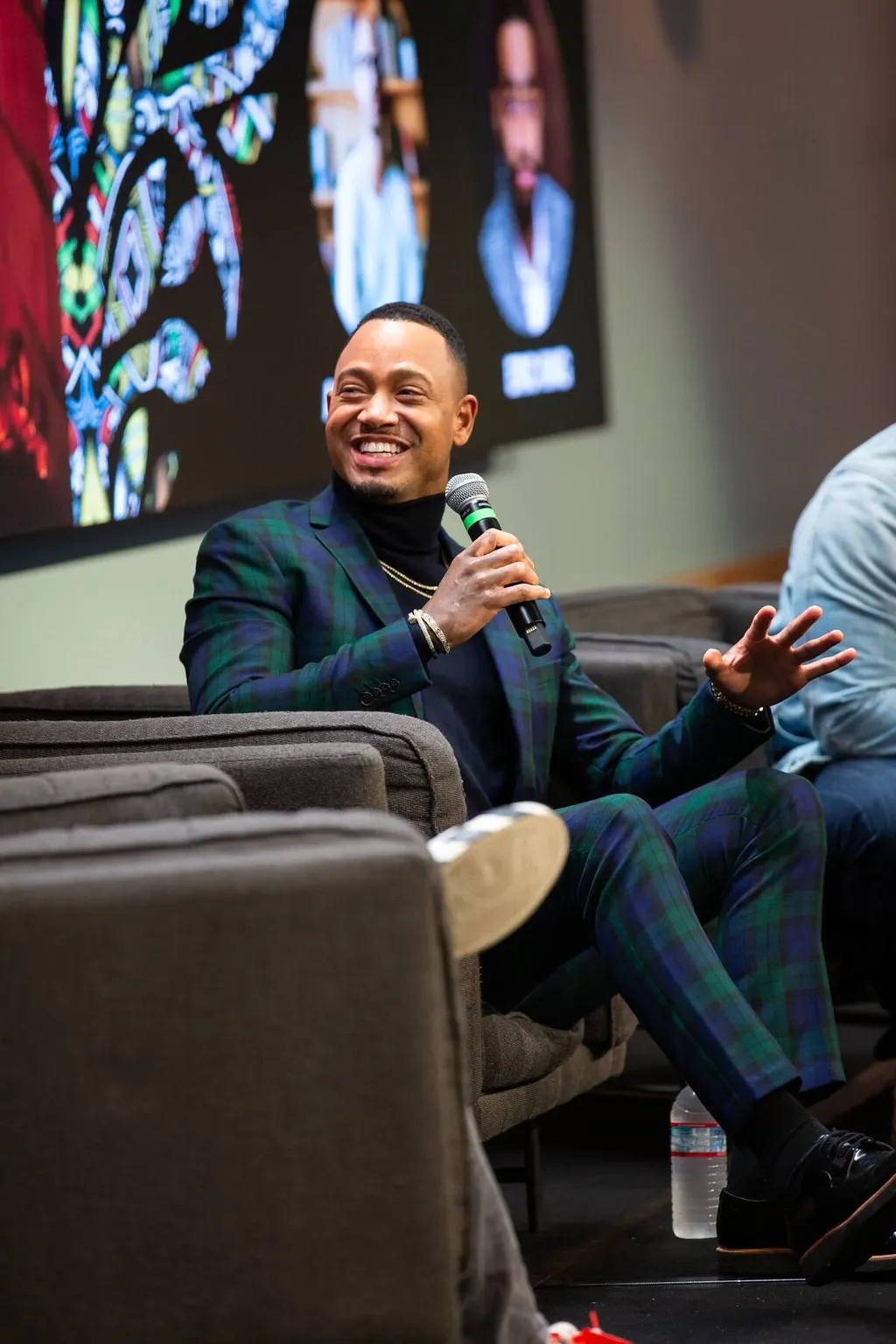 Man speaking into a microphone during a fireside chat panel at a Black Men at Facebook event, photographed by Marquee Visuals.