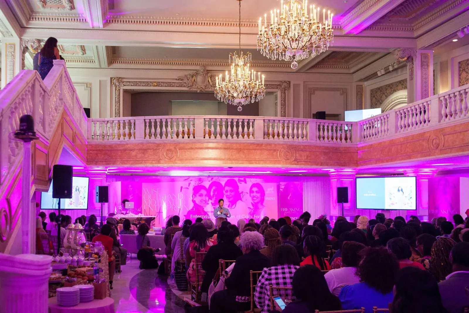 Elegant ballroom set up with purple lighting and chandeliers for the Enterprising Women of Color gala, photographed by Marquee Visuals.