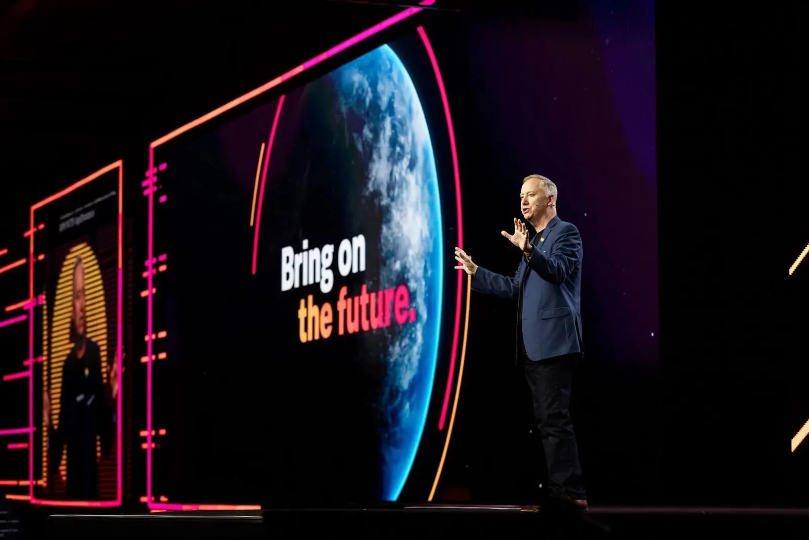 Executive speaker presenting on stage in front of an Earth graphic and 'Bring on the future' tagline on the screen, by Marquee Visuals.