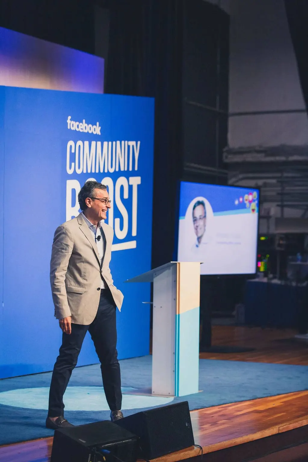 Speaker presenting on stage in front of a Facebook Community Boost branded backdrop in Miami, photographed by Marquee Visuals.
