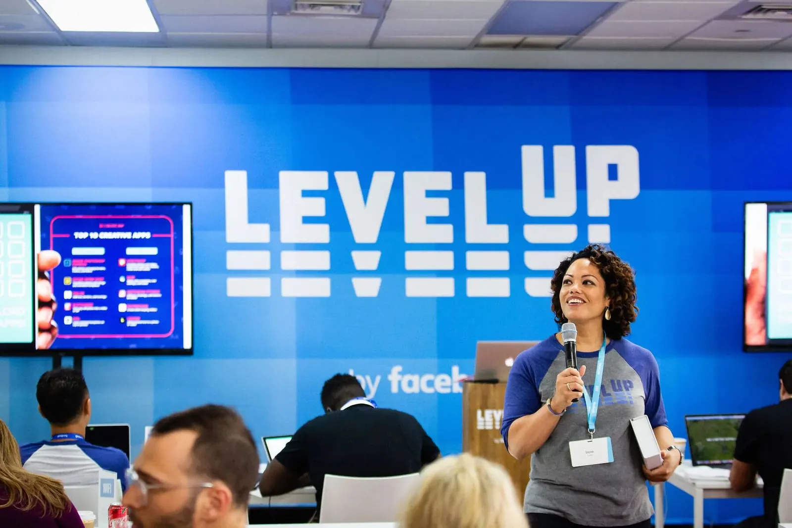 Speaker presenting with a microphone in front of a Level Up branded screen at the Facebook Level Up Miami event, photographed by Marquee Visuals.