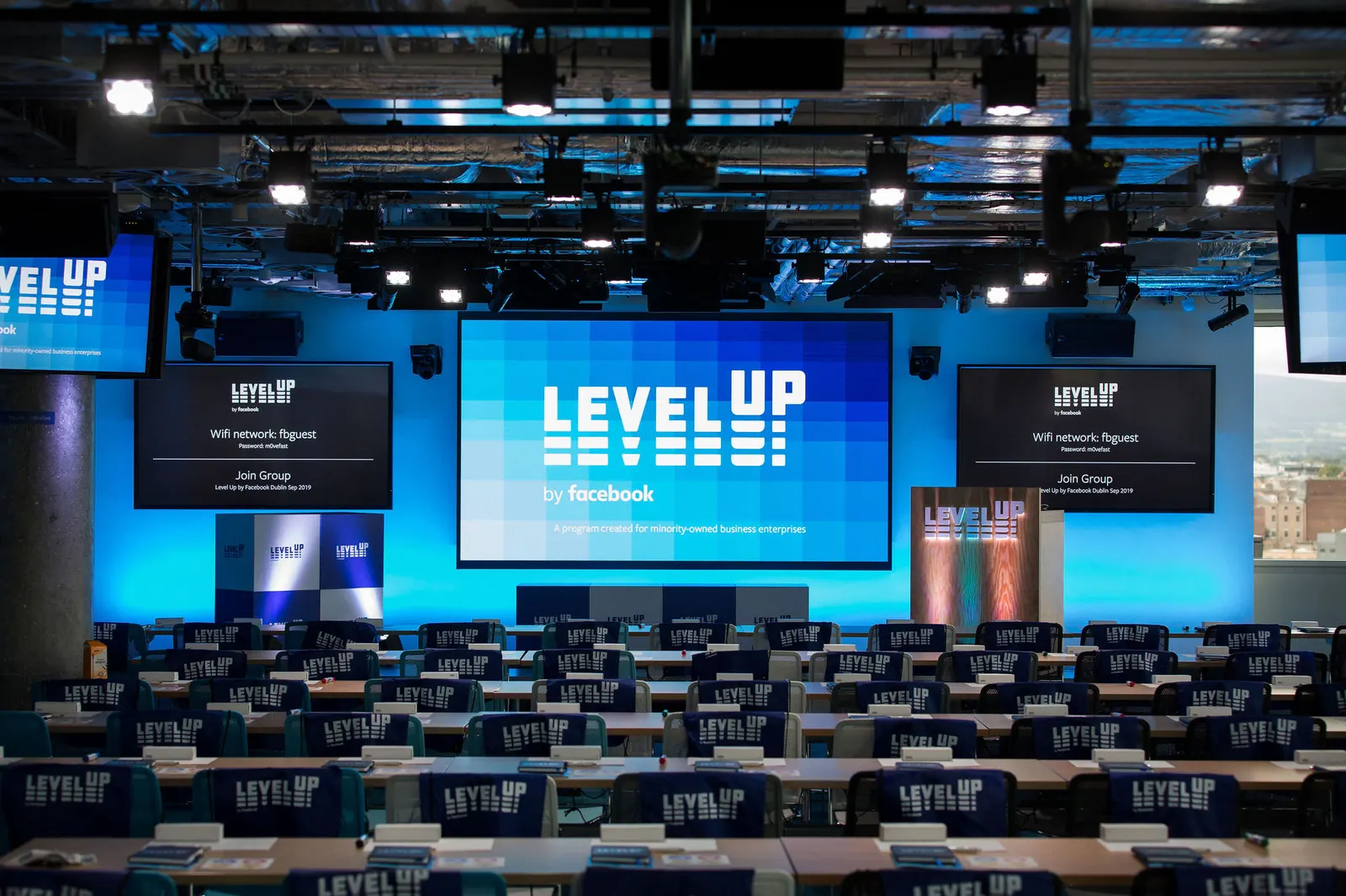 Conference stage with Level Up branding and screens set up for a presentation, photographed by Marquee Visuals.