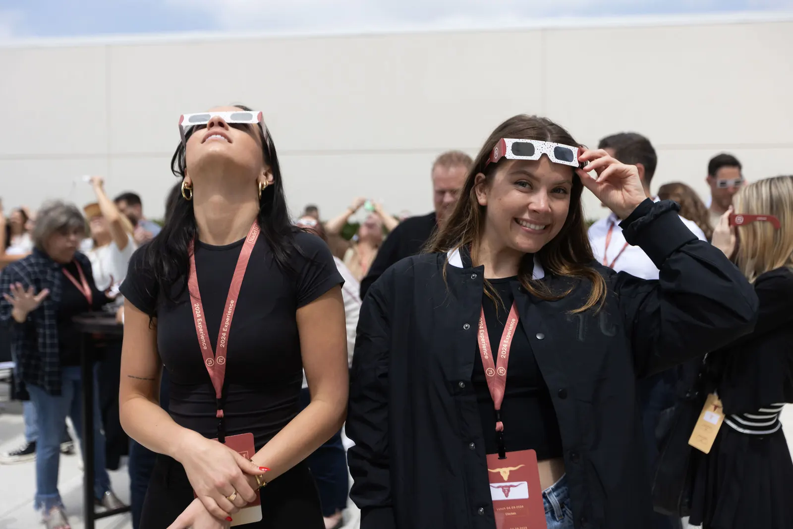Two conference attendees wearing eclipse viewing glasses and looking upward indoors at a corporate event, photographed by Marquee Visuals.