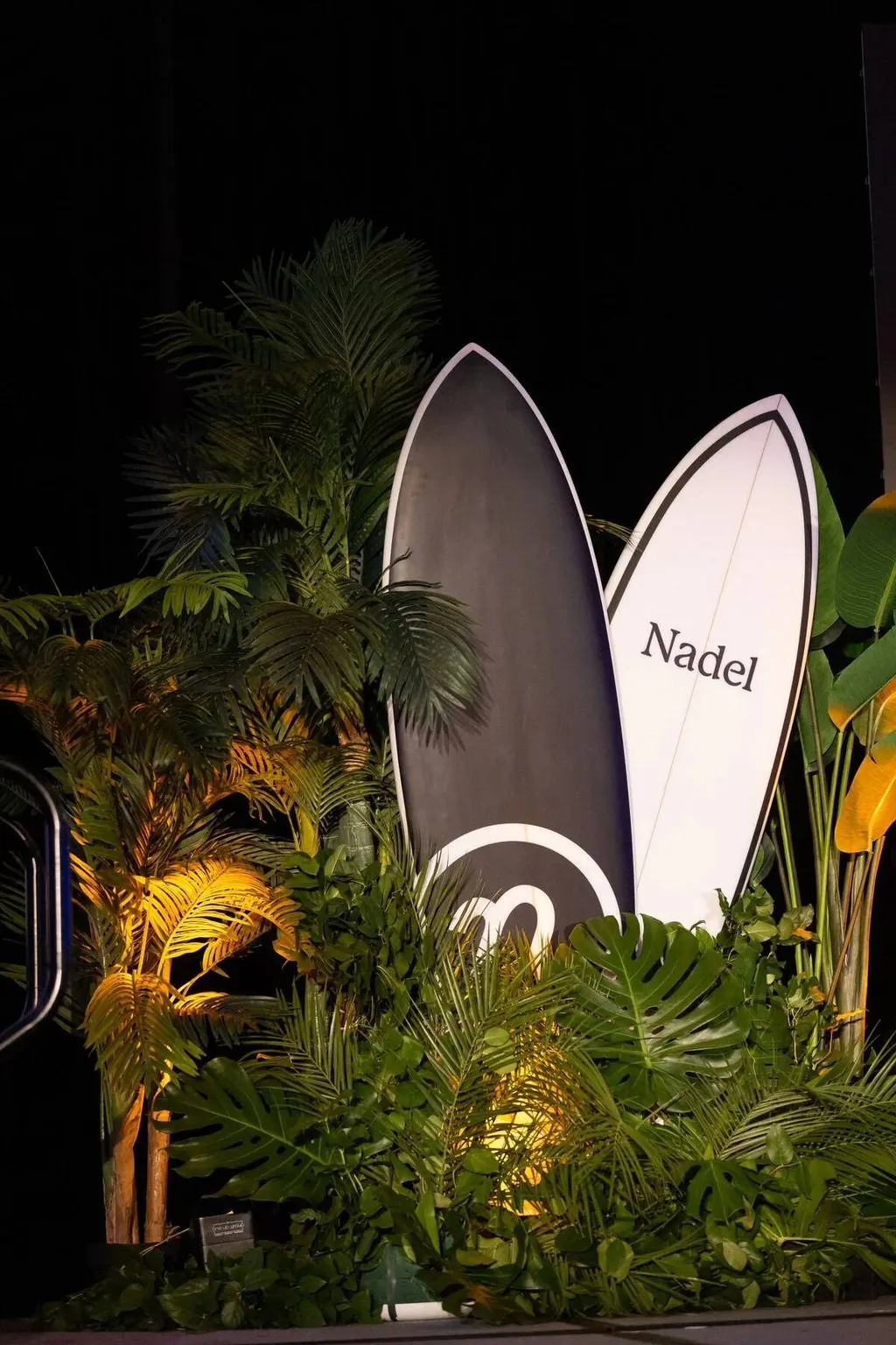 Decorative branded surfboards among tropical plants at the Nadel University 2023 event, photographed by Marquee Visuals.