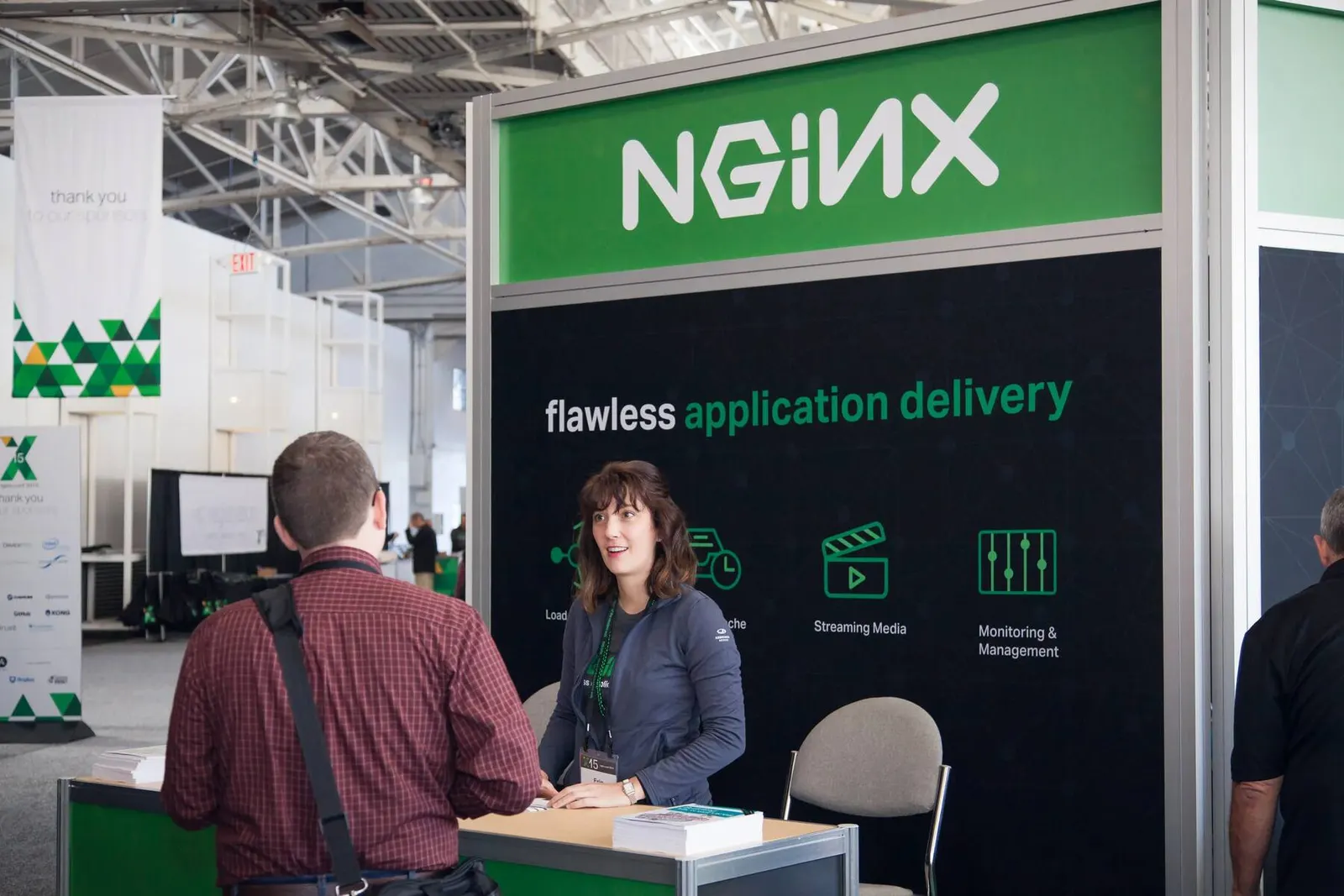 Attendees at an NGINX-branded expo booth reading 'flawless application delivery' at a conference, photographed by Marquee Visuals in the Bay Area.