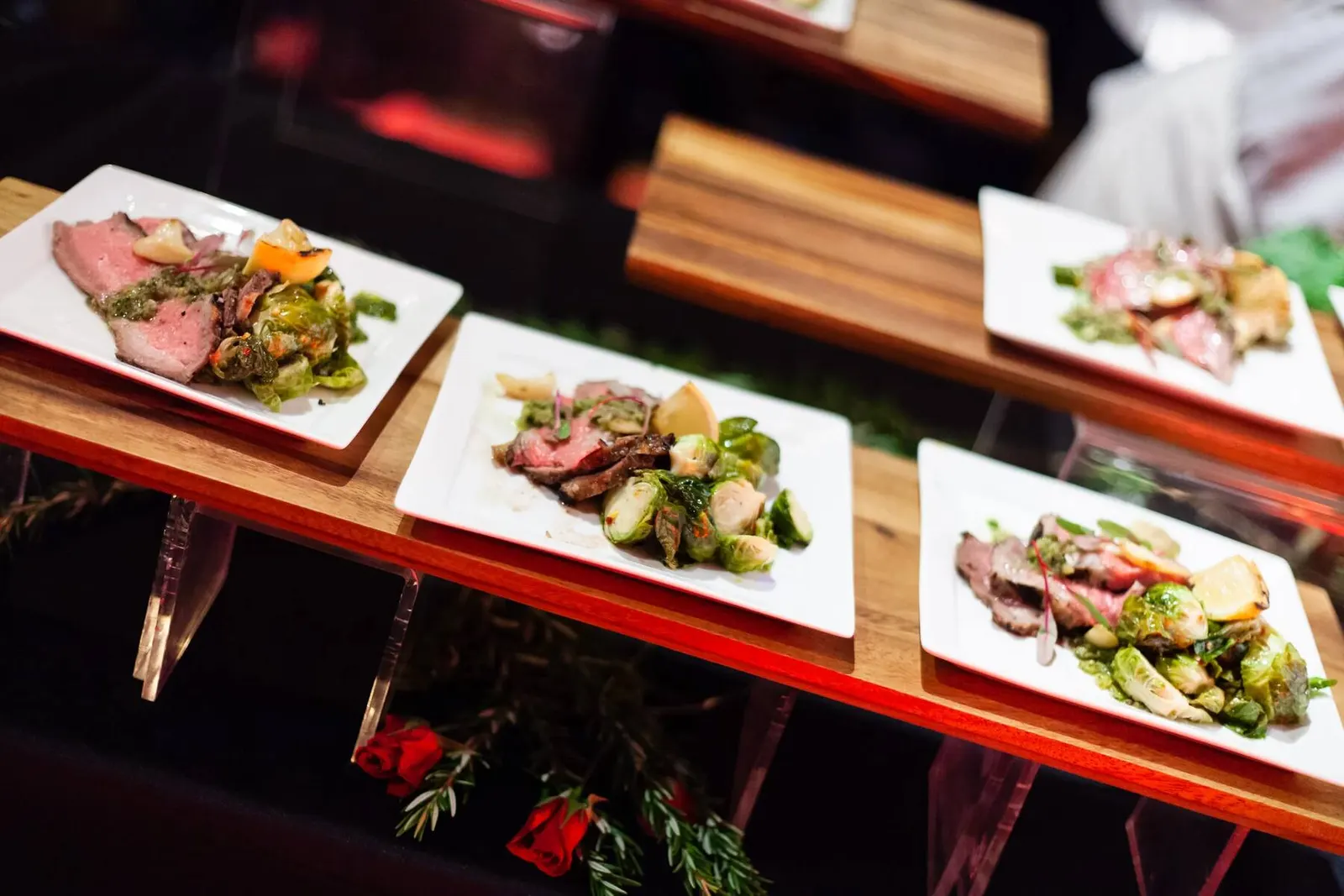 Elegant plated dinner course with steak and roasted vegetables served on a wooden board at a corporate event, photographed by Marquee Visuals.