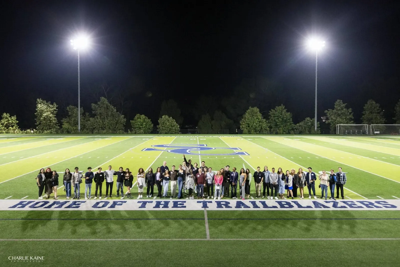 Large group photo of alumni on a football field at night at the Sierra Canyon Alumni Reunion, photographed by Marquee Visuals.