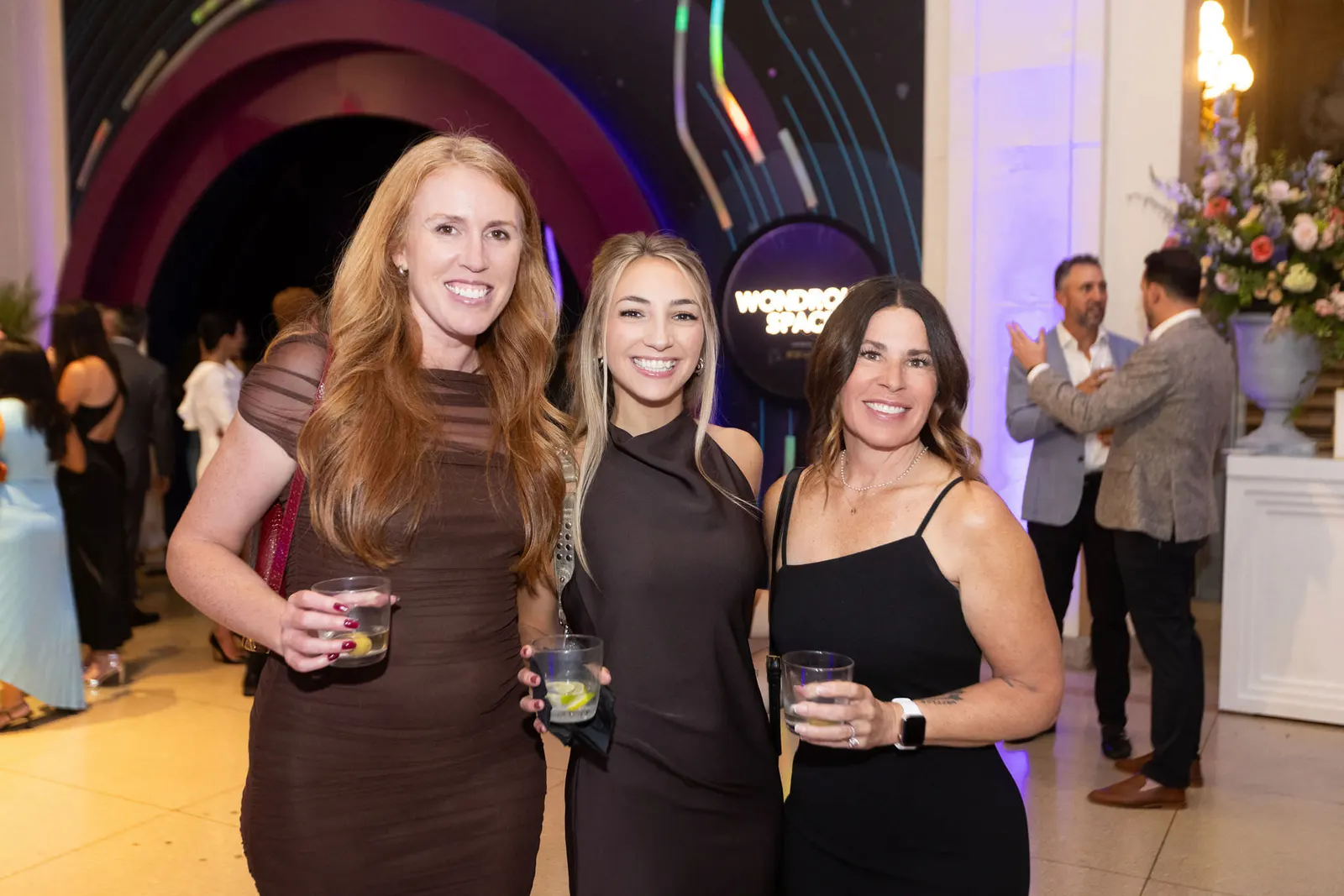 Three women posing together at a gala cocktail reception, photographed by Marquee Visuals in Los Angeles.