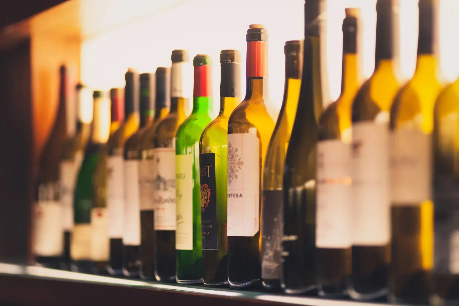Close-up detail of wine bottles displayed on a shelf at the Tron Happy Hour event, photographed by Marquee Visuals.