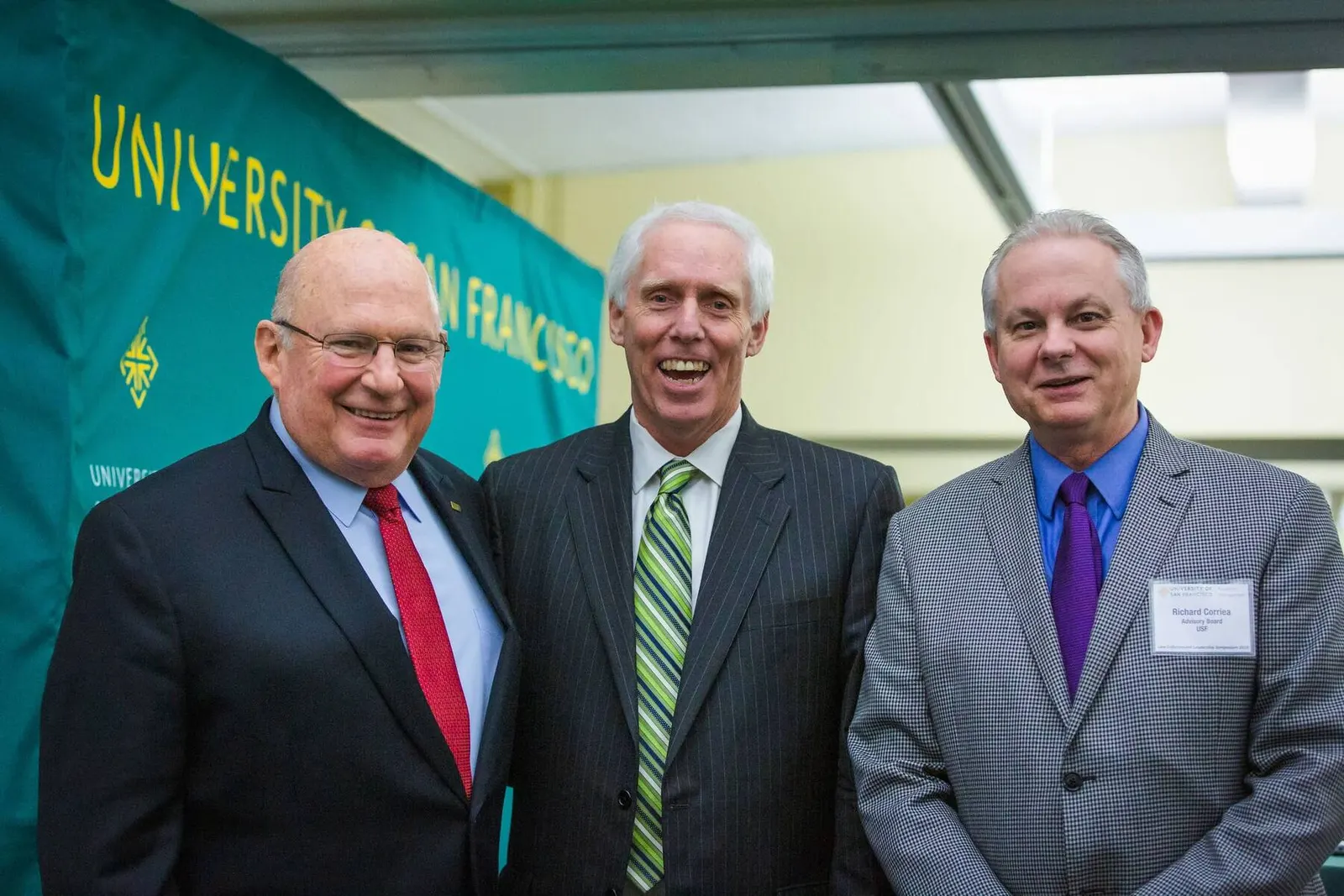 Three men in suits posing together at the University of San Francisco Law Enforcement Symposium, photographed by Marquee Visuals.