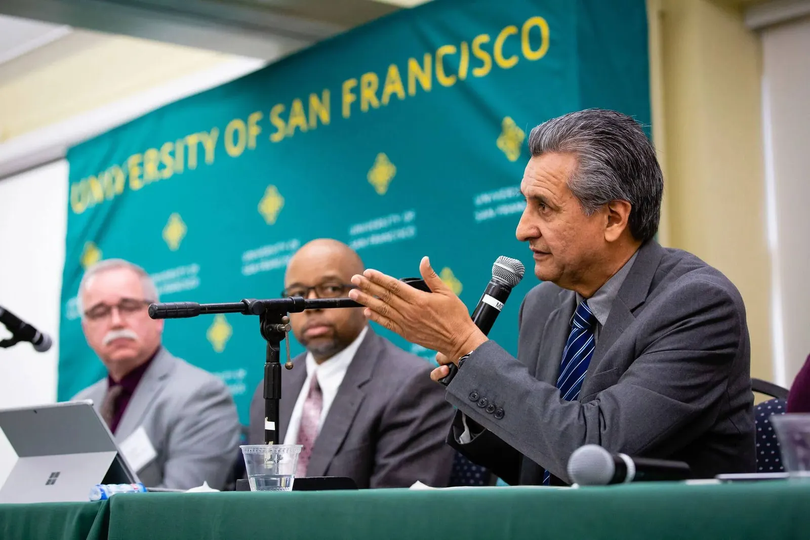 Panel of three speakers seated at the University of San Francisco Law Enforcement Symposium, photographed by Marquee Visuals.