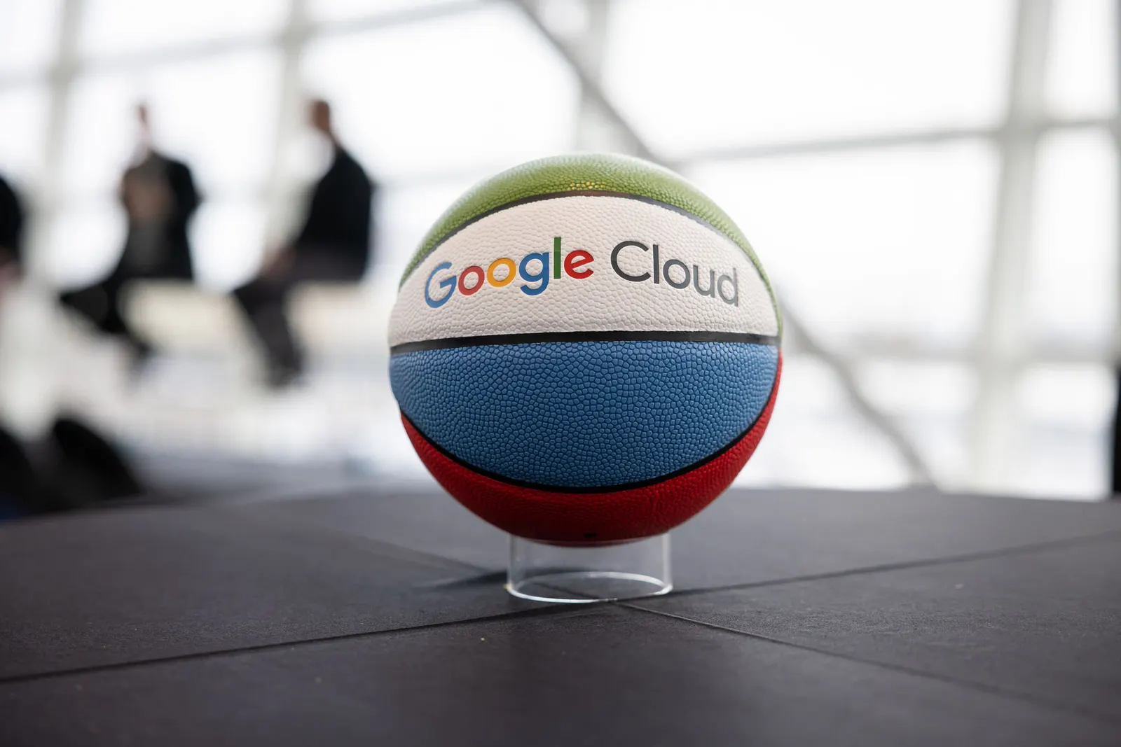 Basketball on a display stand with Google Cloud branding, arena background softly blurred, photographed by Marquee Visuals.