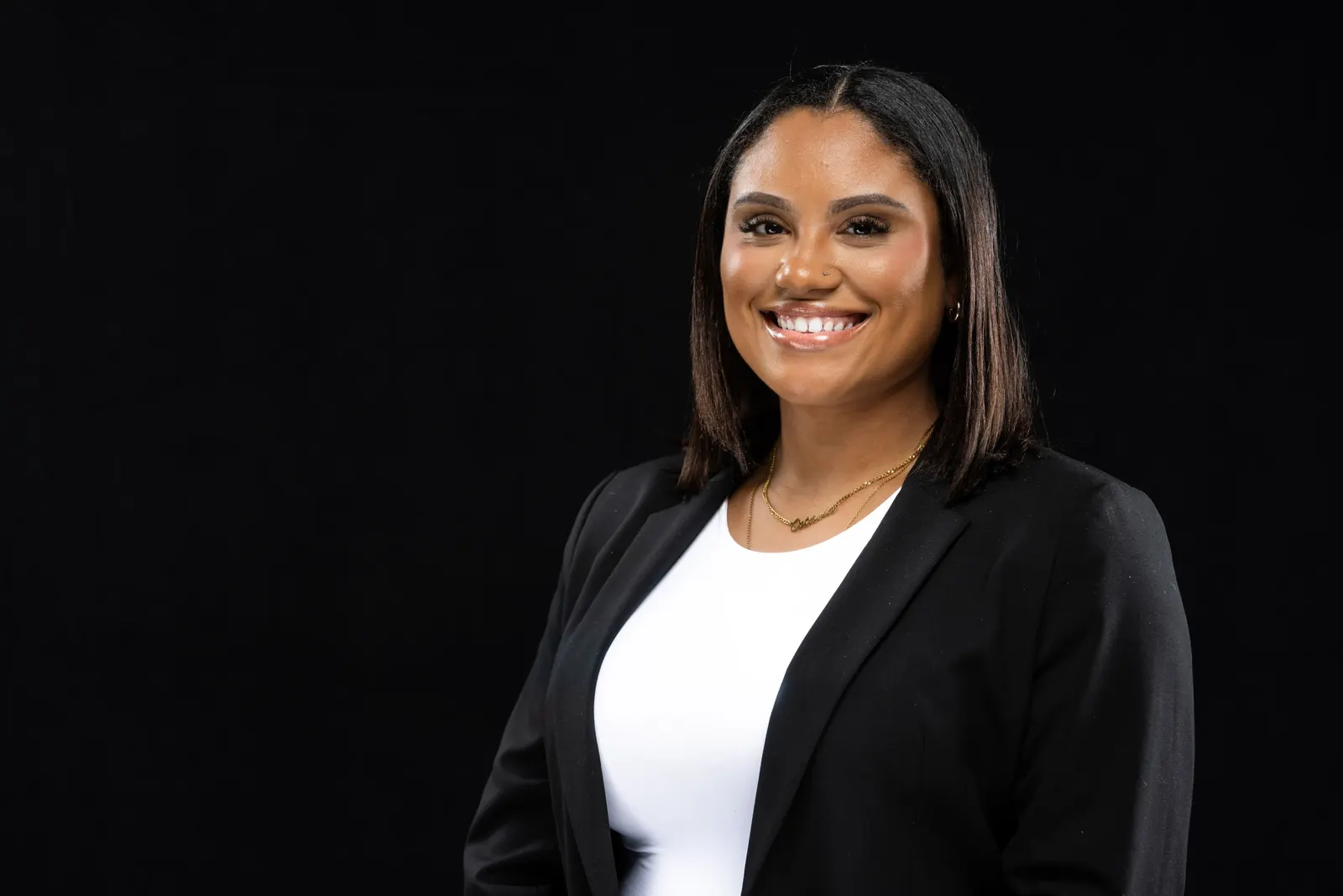 Corporate headshot of a smiling woman in a gray quarter-zip top on a black studio backdrop, photographed by Marquee Visuals in Los Angeles.